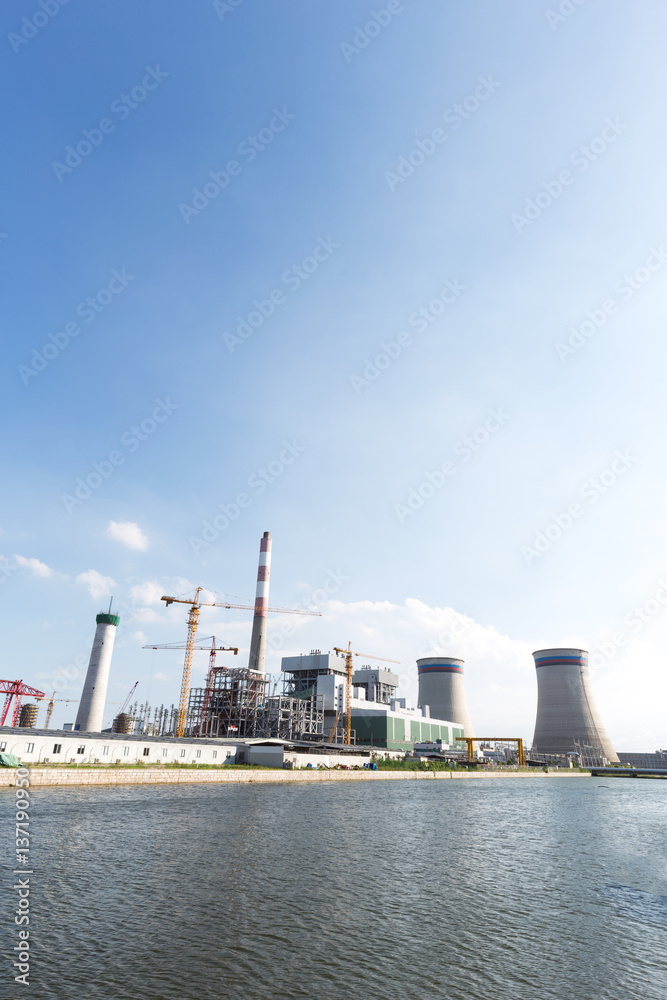 modern power plant near river in blue sky