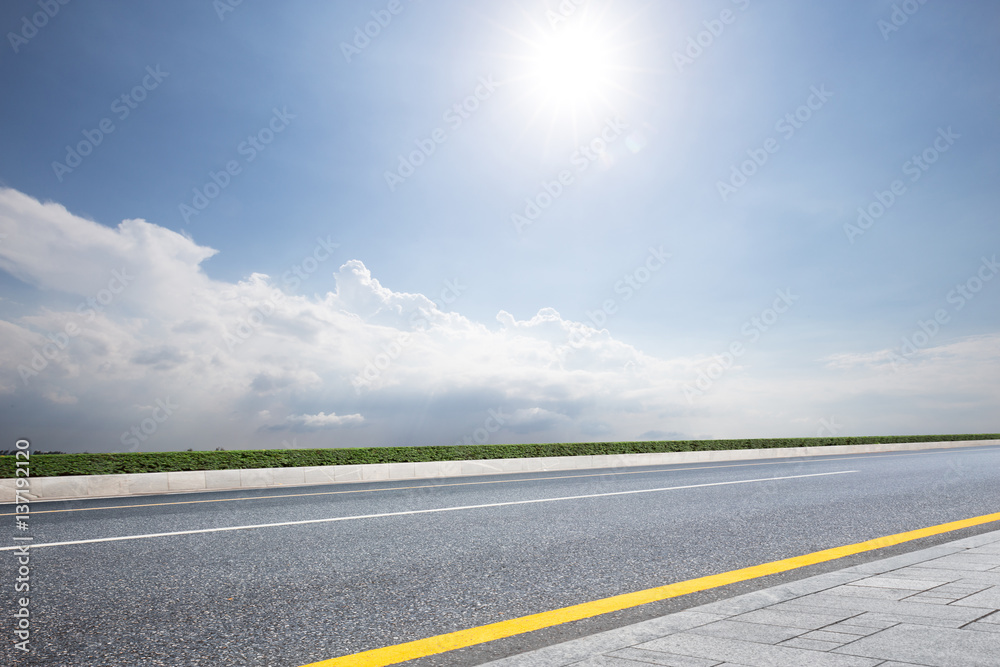 empty asphalt road in blue sunny sky