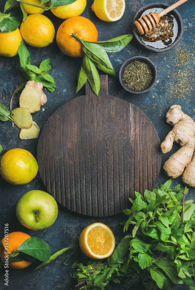 Ingredients for making natural drink with wooden round board in center. Oranges, mint, lemons, ginge