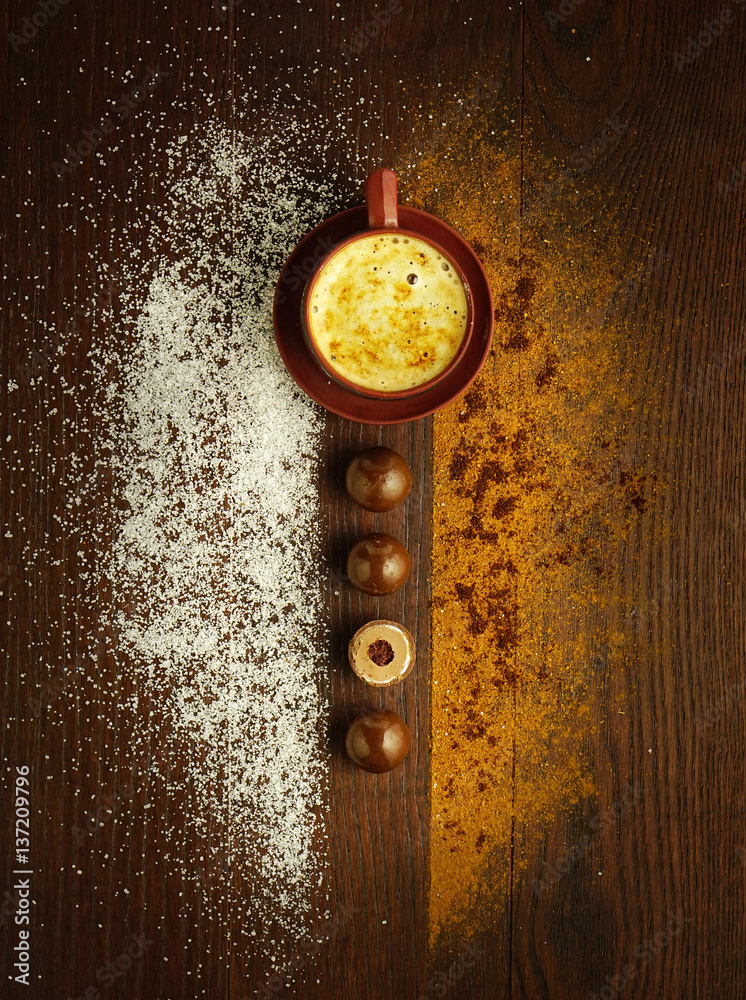 Cup coffee on brown wooden table with chocolates. Sugar and cinnamon sprinkled on table. Beautiful o