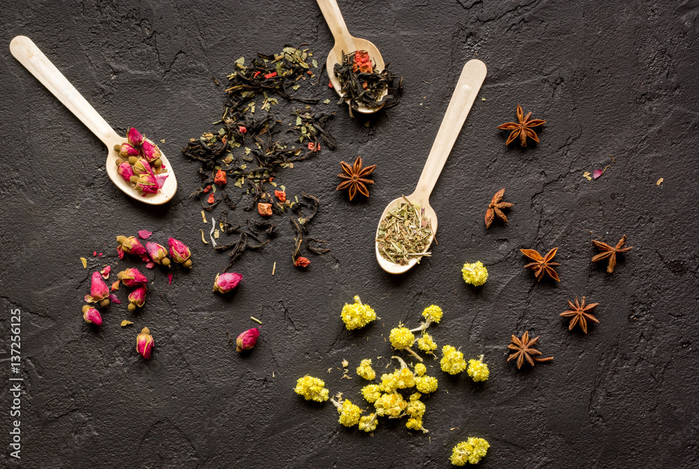 Herbs and spoons on black background top view