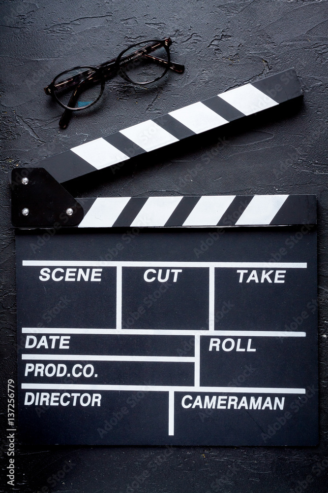 Screenwriter desktop with movie clapper board dark background top view