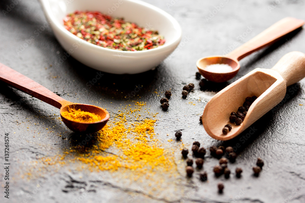 spices in wooden spoon on dark background