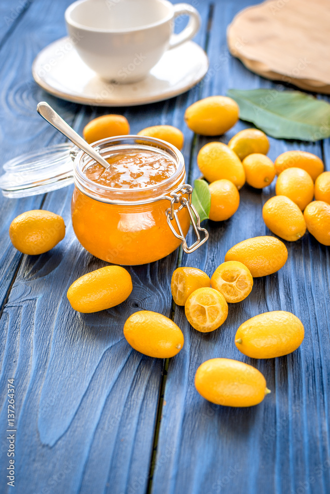 kumquat on plate and jam in jar at wooden table