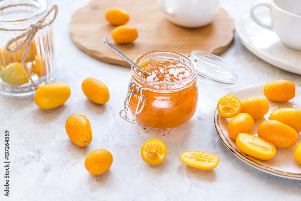 kumquat on plate and jam in jar at gray background