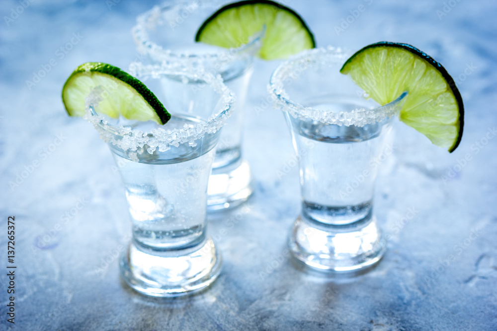 Silver tequila shots with lime and salt on gray stone background