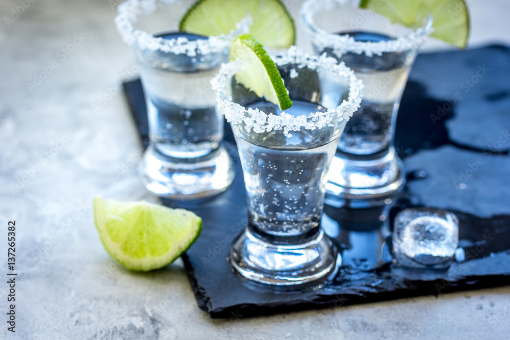 Silver tequila shots with lime and salt on gray stone background