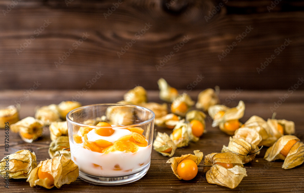 yogurt with physalis on wooden background