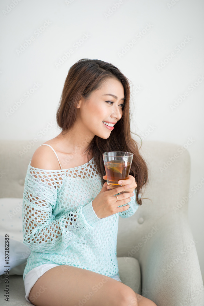 Beautiful young asian woman drinking her morning tea over a breakfast at home.