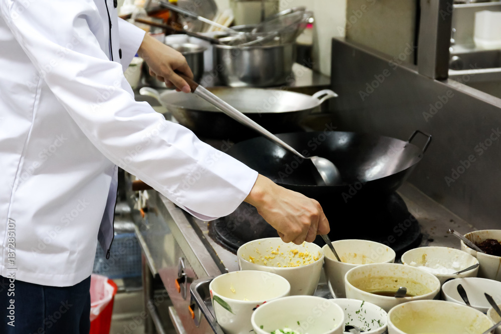 Chef in hotel or restaurant kitchen busy cooking