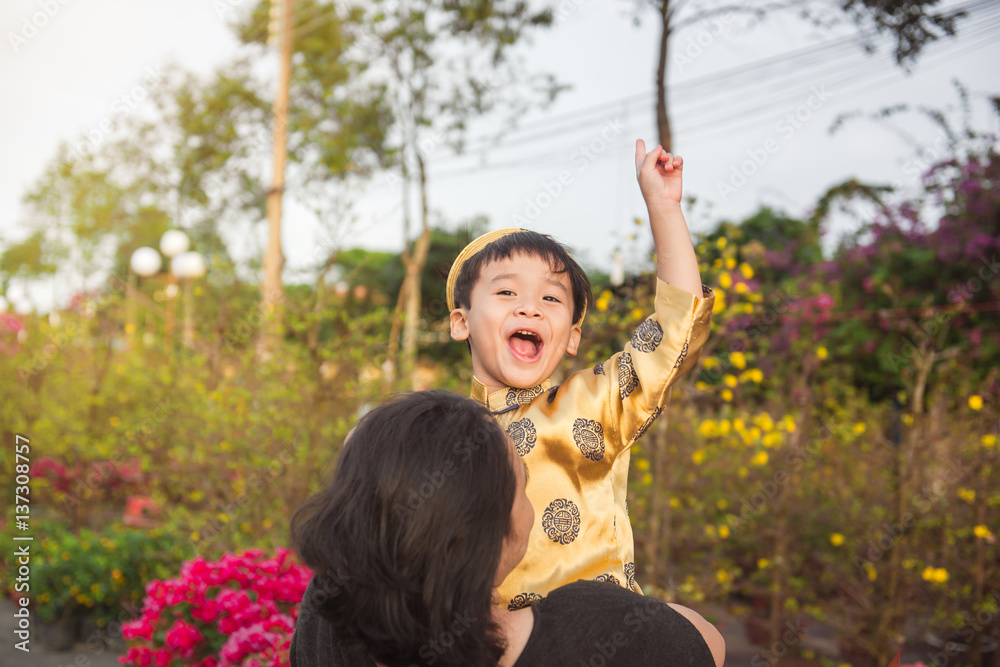 Happy kid having fun in traditional dress  Ao Dai with mom.