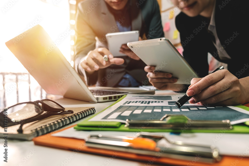 businessman documents on office table with smart phone and laptop and two colleagues discussing data