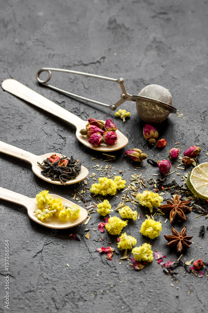 Spoons with herbs on dark stone background