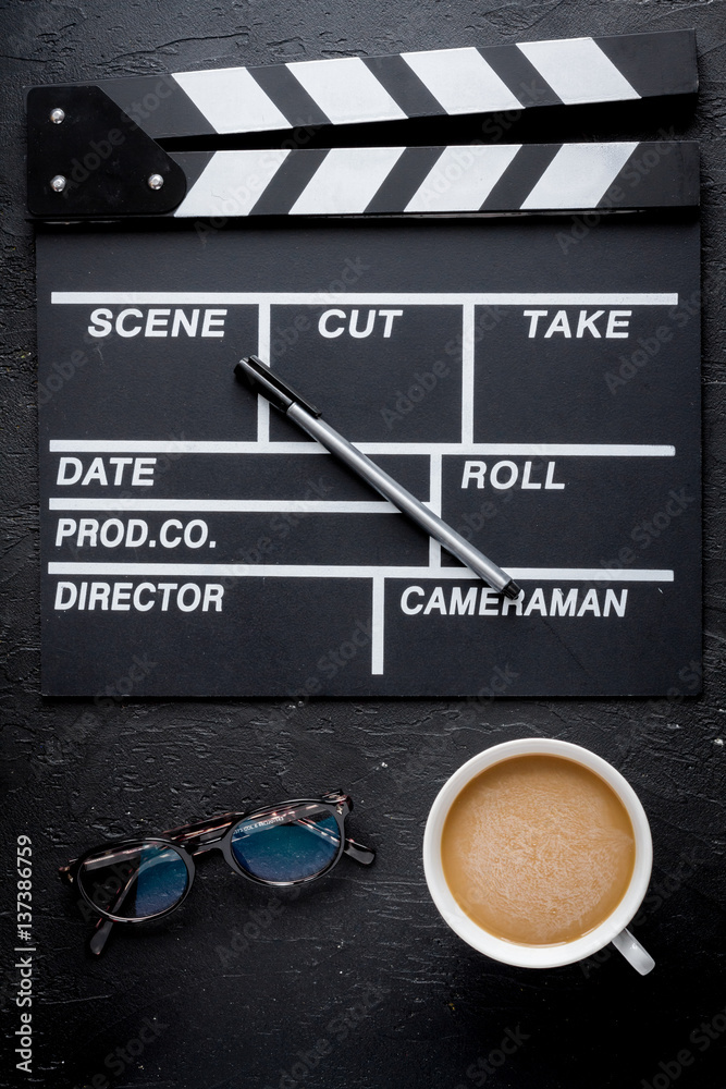 Screenwriter desktop with movie clapper board dark background top view