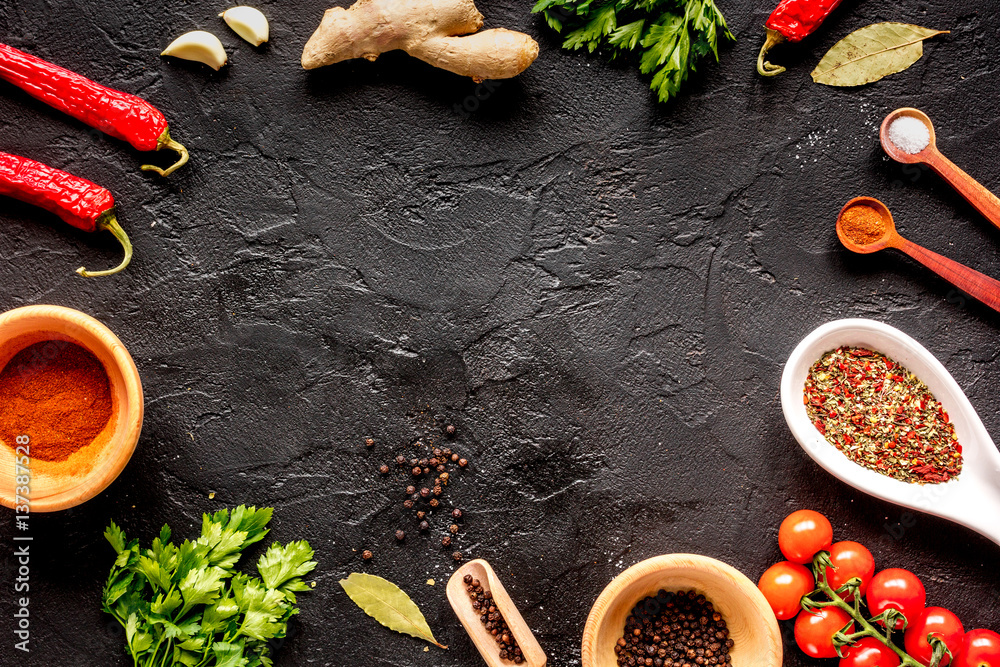 spices in wooden spoon on dark background top view