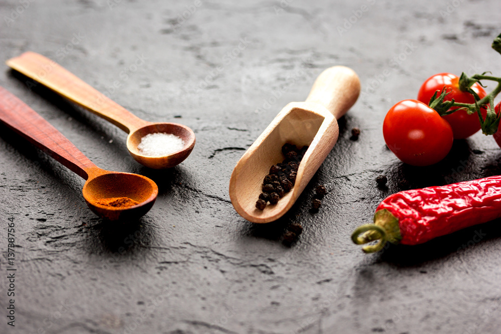 spices in wooden spoon on dark background