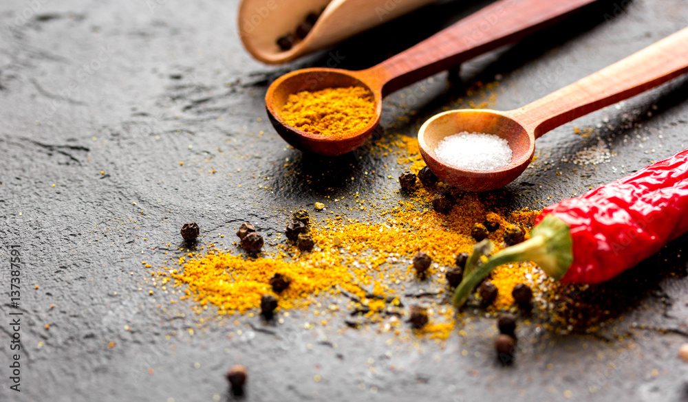 spices in wooden spoon on dark background