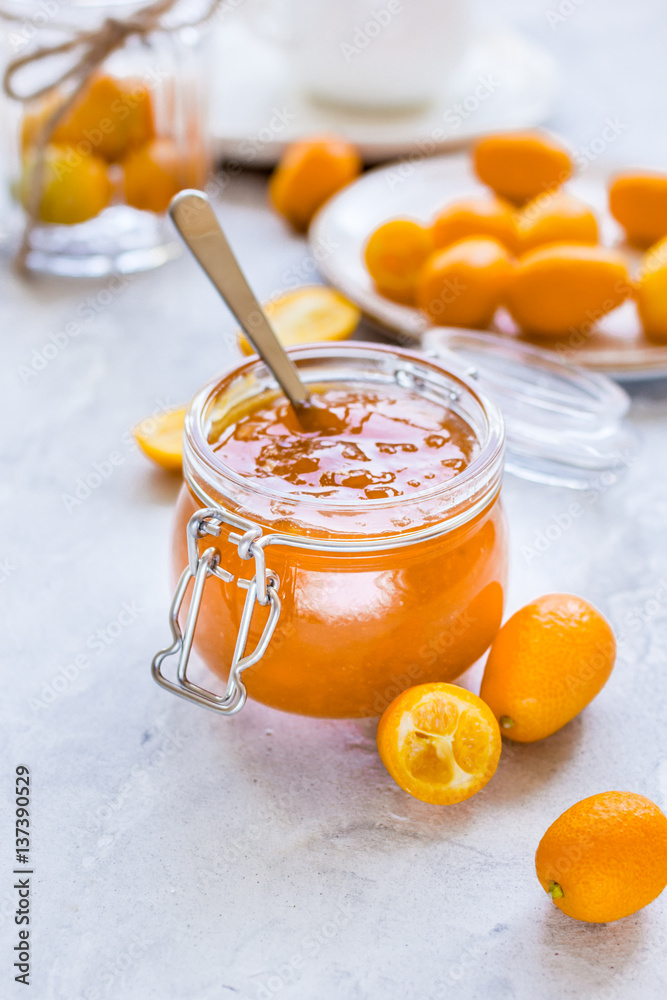 kumquat on plate and jam in jar at gray background