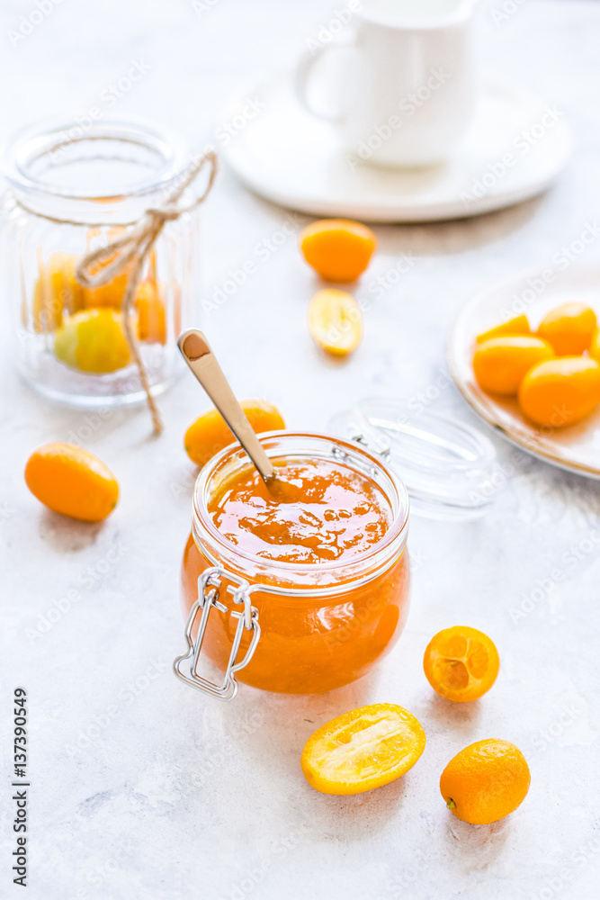 kumquat on plate and jam in jar at gray background