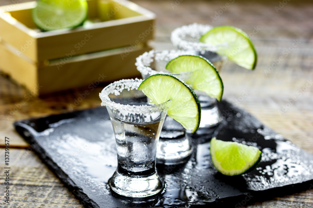 Bar set with shots, fresh lime and salt on wooden background