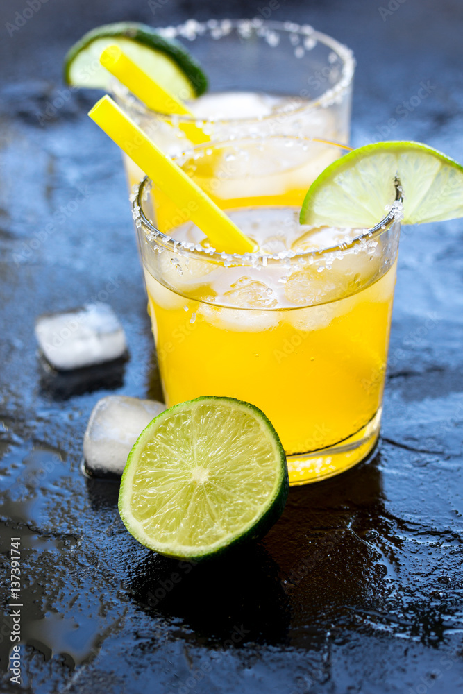 Alcohol cocktails with lime and ice on dark background