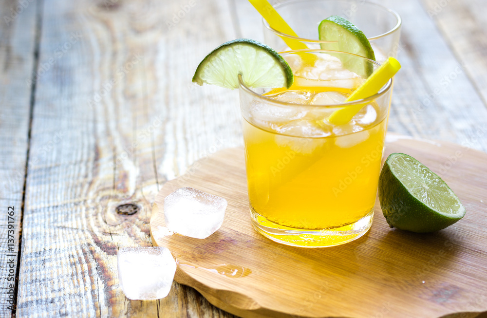 Alcohol orange cocktails with lime and ice on wooden background