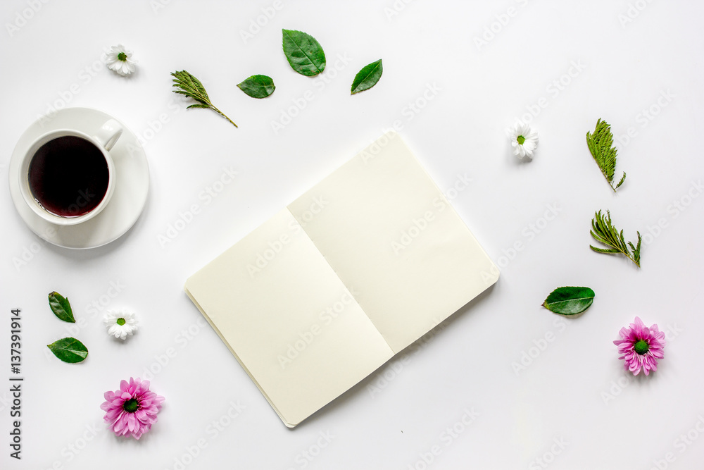 Petals, cup and copybook on table background top view mock up