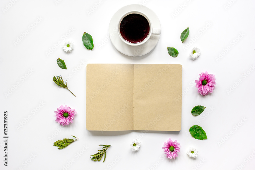 Petals, cup and copybook on table background top view mock up