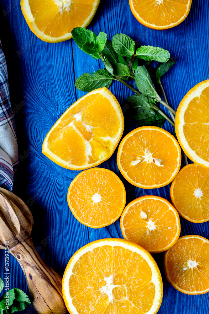 cut oranges with mint leaves and towel on blue kitchen top view