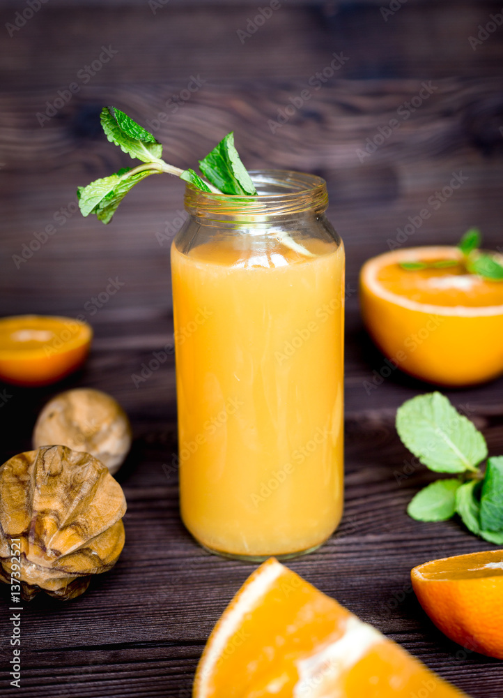 healthy orange cocktail with mint leaves in bottle on kitchen background