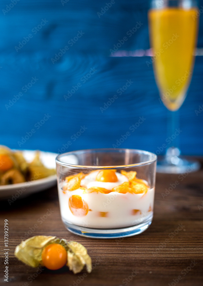 yogurt with physalis on wooden background