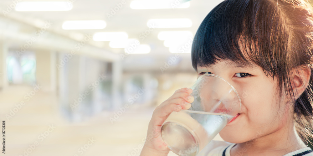 Girl holding glass with water. Happy child at summer