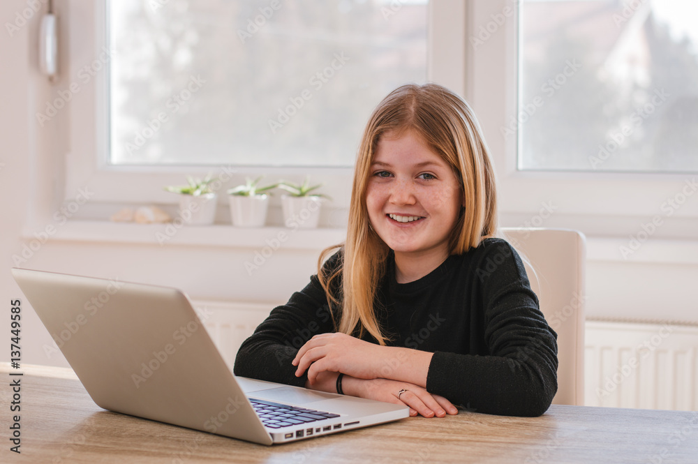 Portrait of smiling young girl with computer at home