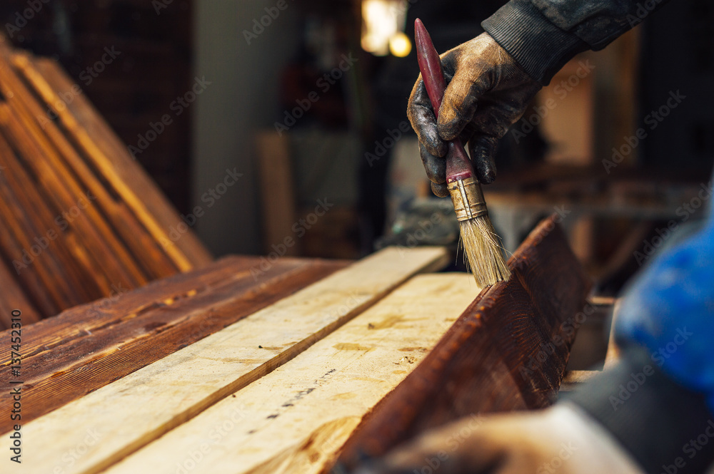 Close up paintbrush in hand and painting on the wooden table.