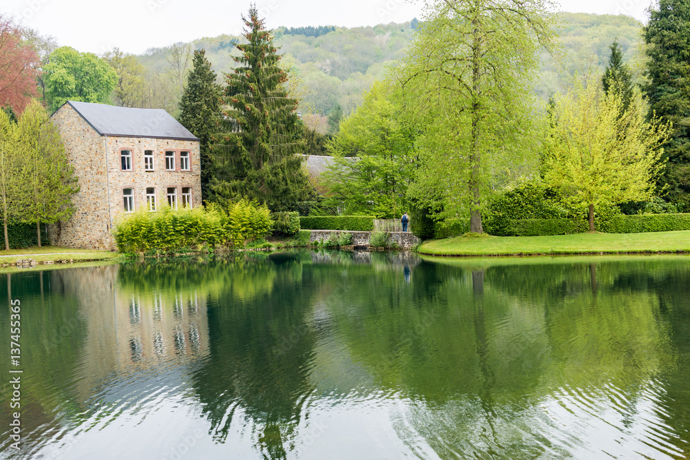 Maison au bord dun lac. Reflet des arbres sur leau. Petit pont.