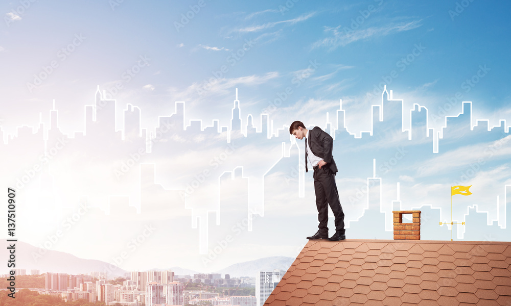 Businessman looking down from roof and modern cityscape at background. Mixed media