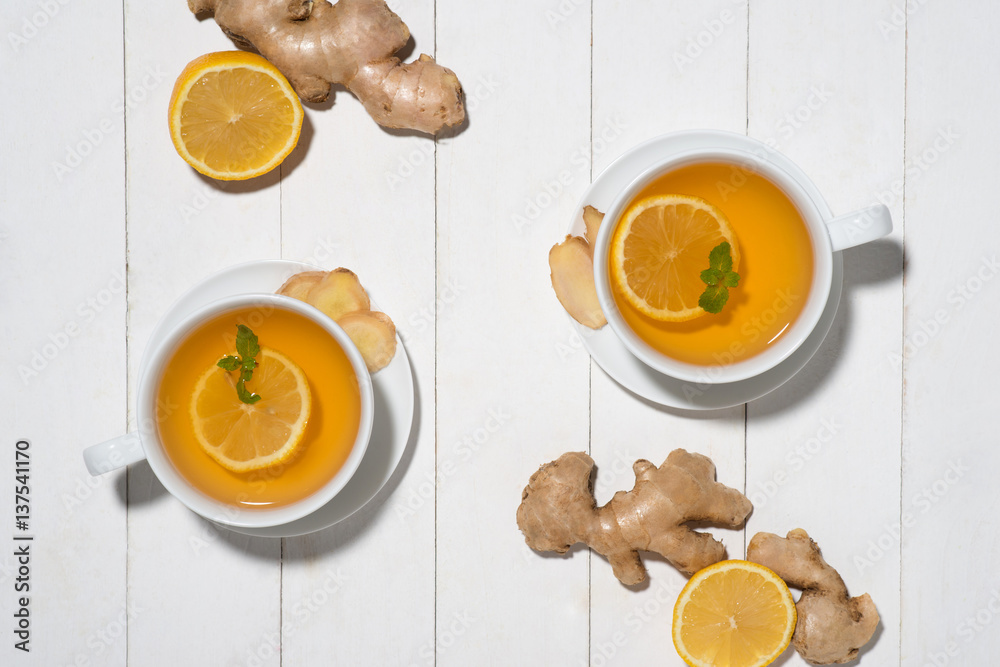 Cup of Ginger Tea with Lemon and Honey on a White Wooden Background.