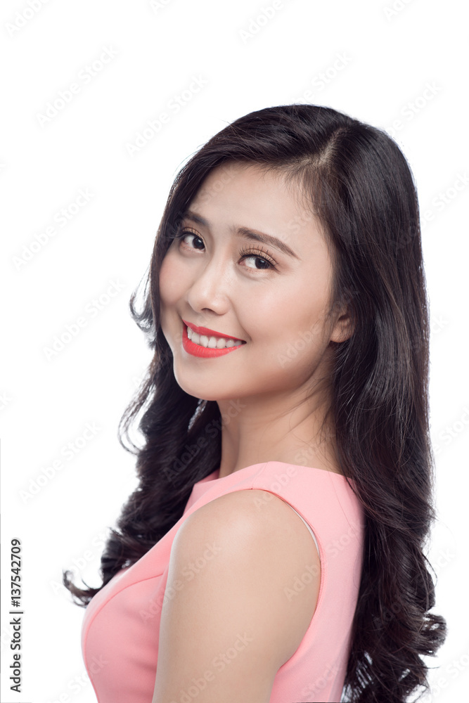 Asian young beautiful woman with long black hair in pink dress standing over white.