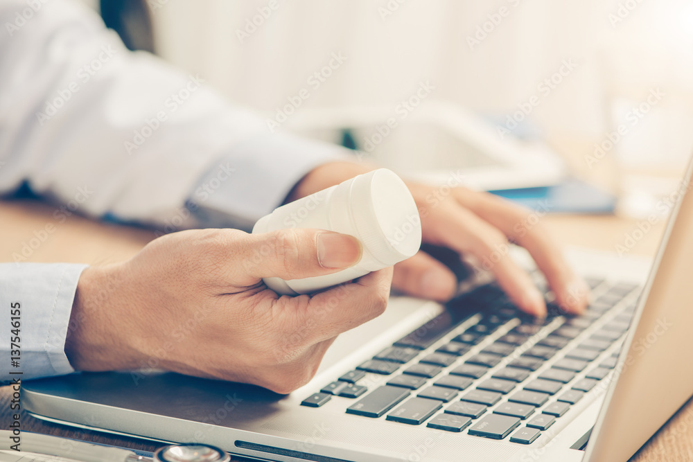 Male doctor working at wooden desk in clinic