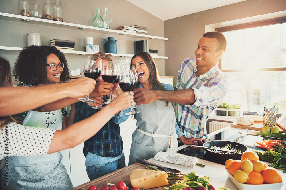 Group of friends cheering at kitchen.