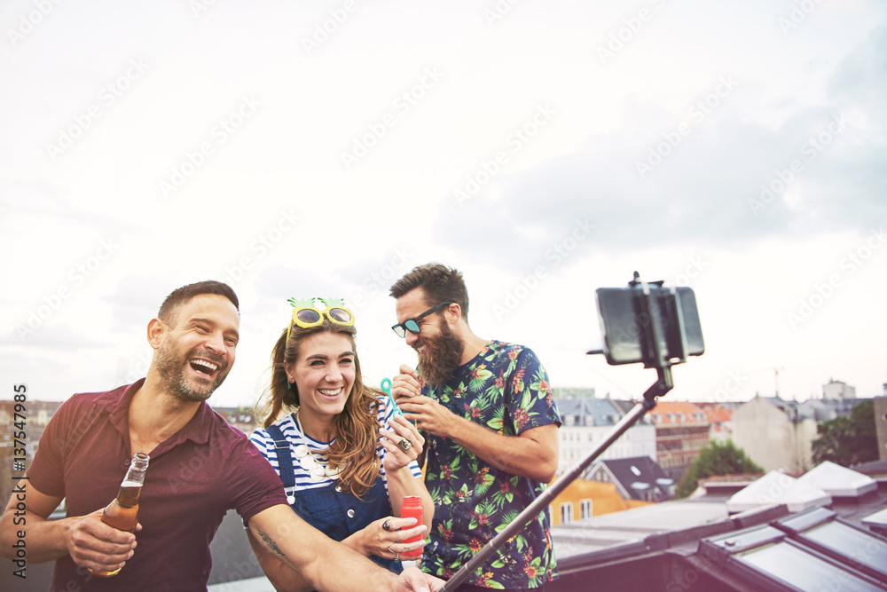 Three happy friends taking pictures of themselves