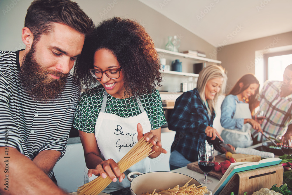 Friends making pasta dinner in small kitchen