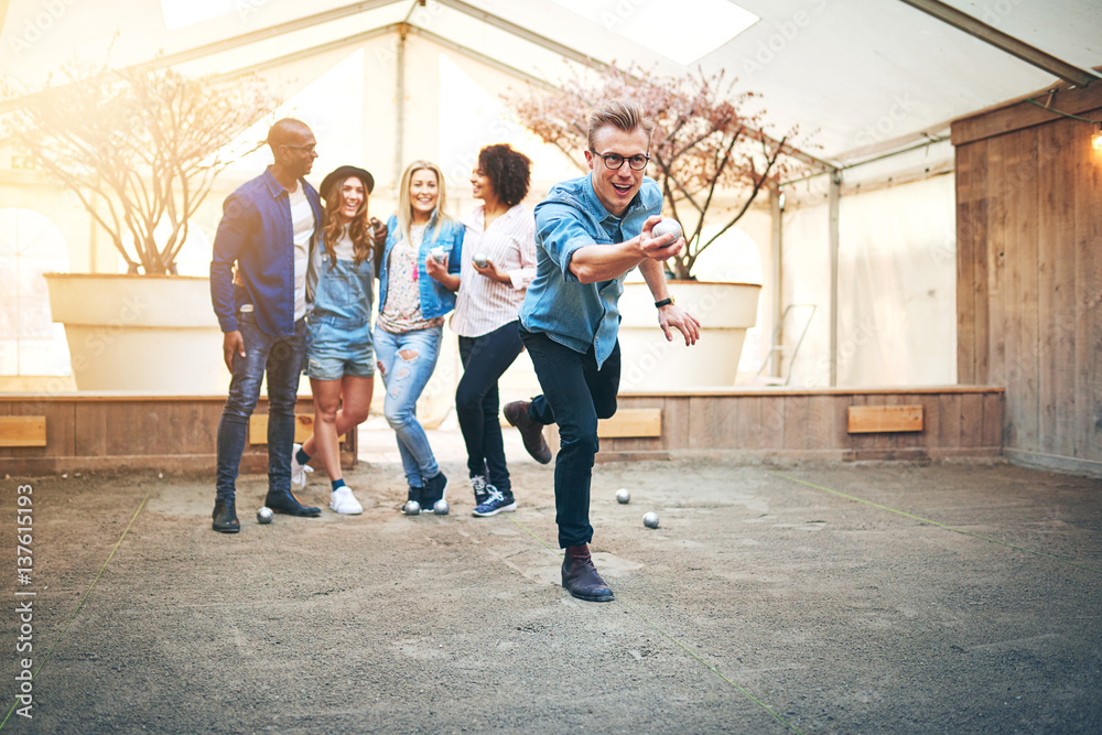 Guy playing petanque indoors with friends