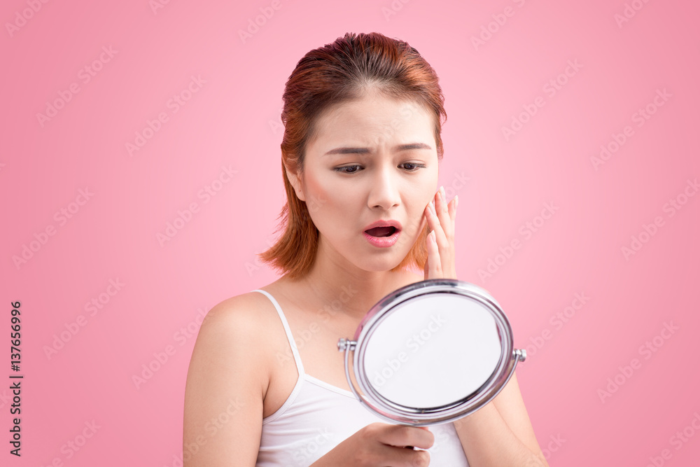 Pretty young asian woman holding a mirror, touch and worrying about her face