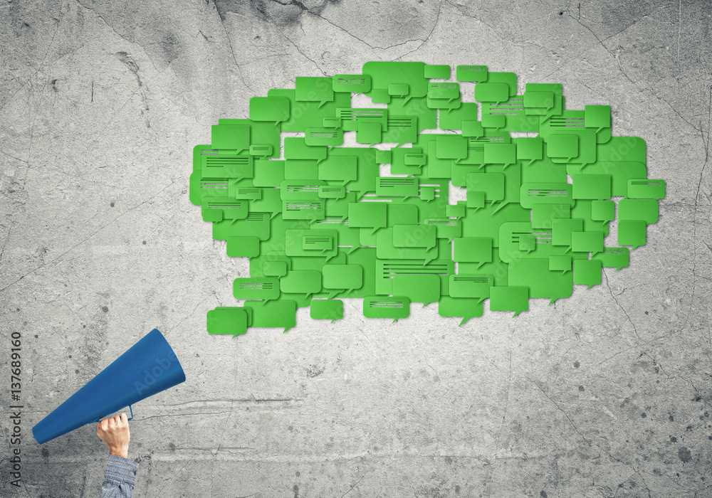 Hand of woman holding green paper trumpet and speech cloud coming out