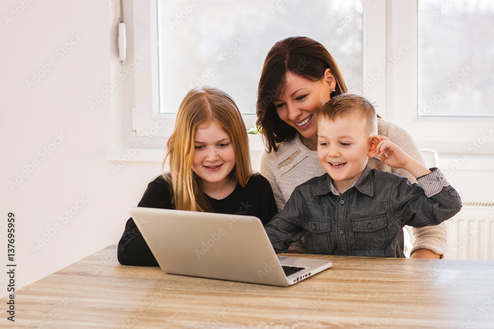 Happy loving family. Mom and kids playing on computer at home.