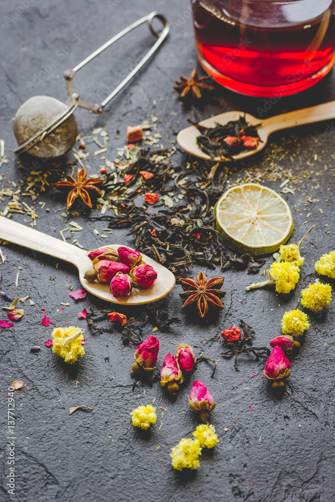 Teacup and herbs on dark stone background