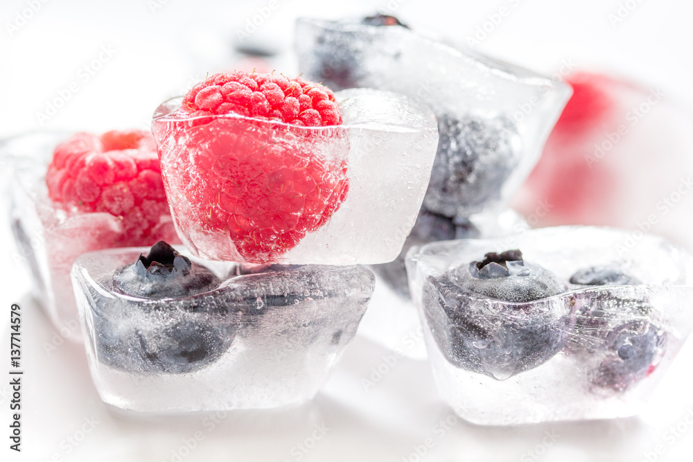 frozen blueberry and raspberry in icecubes on white background