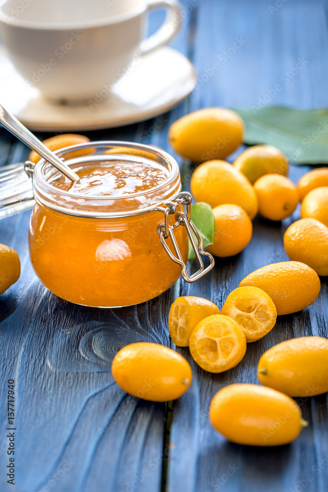 kumquat on plate and jam in jar at wooden table