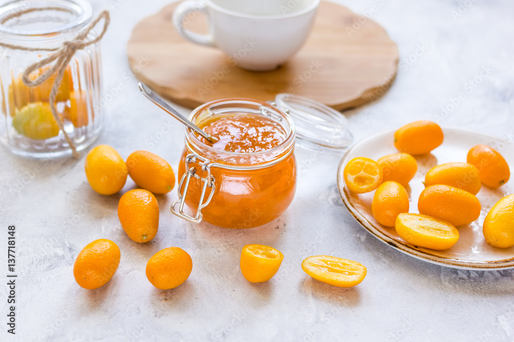 kumquat on plate and jam in jar at gray background